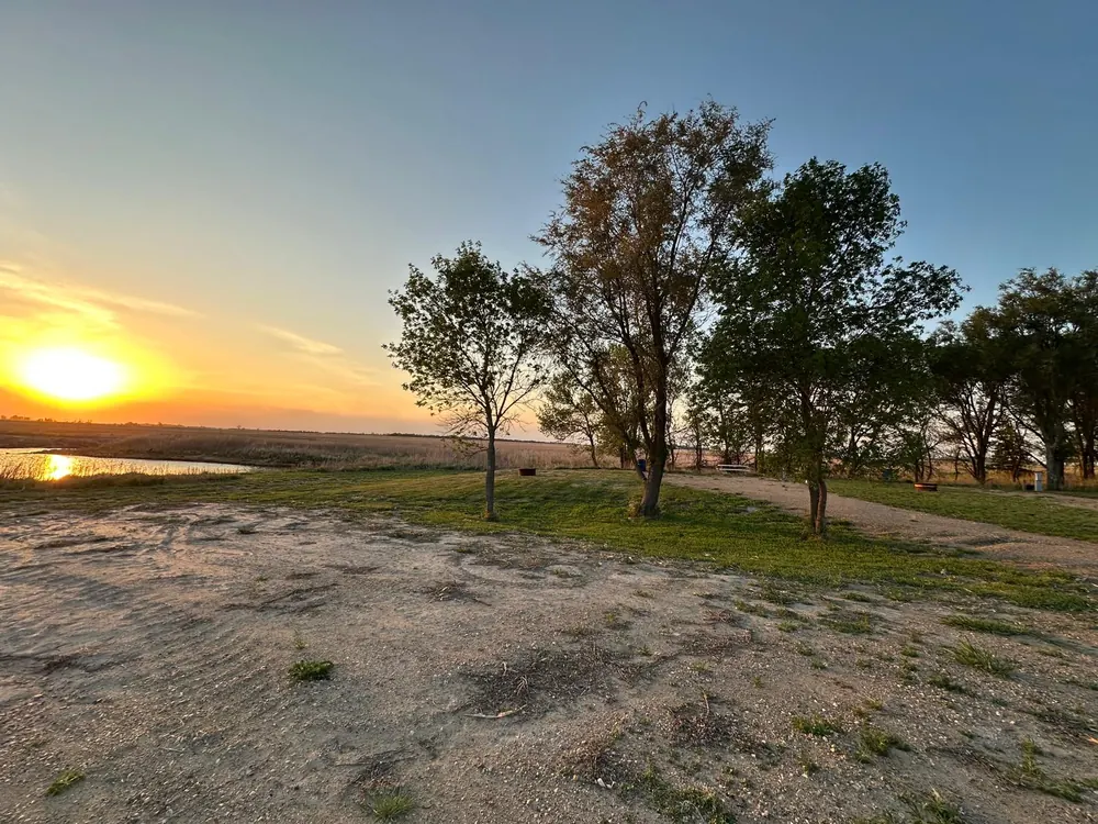 Sunset over the open campground sites with water in the distance